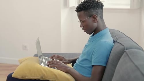 Young Adult Typing on Laptop Computer at Home