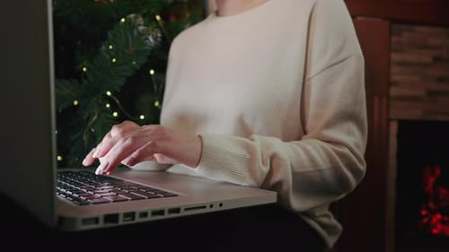 Typing on Laptop by Christmas Tree and Fireplace