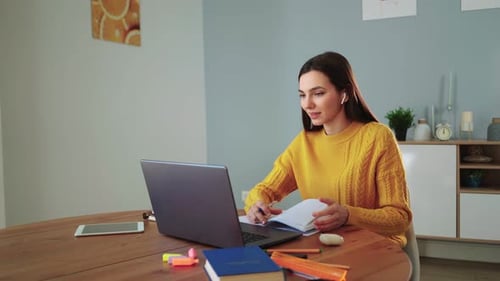 Woman Works on Laptop and Writes in Notebook
