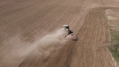Aerial View of Tractor Cutting Furrows in Farm Field for Sowing Farm Tractor with Rotary Harrow Plow