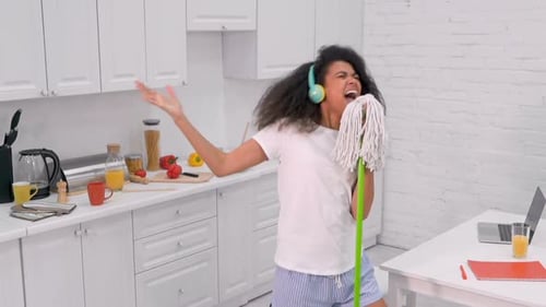 Woman Singing into Mop in Kitchen