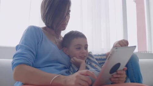 Woman and Child Using Tablet Together on Sofa