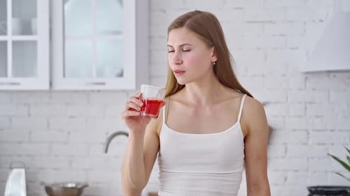 Young Woman Drinking Refreshing Red Juice at Home