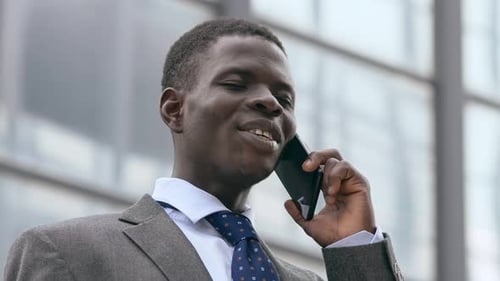 Smiling black american business man talking by phone in the street