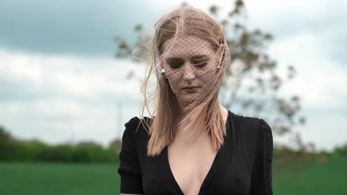 Woman in Veil Stands in Windy Rural Field
