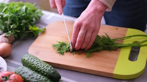 Woman Cutting Fresh Dill on Cutting Board