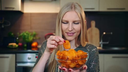 Woman Eating Potato Chips in Kitchen