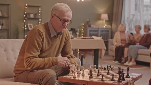 Senior Man Plays Chess with Friend at Home