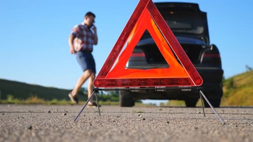 Close Up of Red Emergency Stop Sign Standing on Road. Worried and Angry Driver Walking Near His