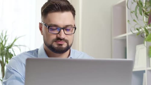 Bearded Man Working at a Laptop