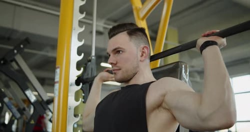 Muscular Athlete Works Out in Modern Gym Making Seated Barbell Shoulder Press