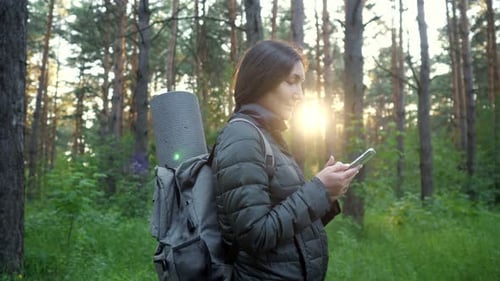 Woman Using Phone While Hiking in Forest