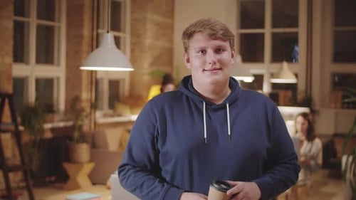 Portrait of Joyous Young Man with Coffee Cup in Loft Office