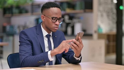 Serious African Businessman Using Smartphone in Office
