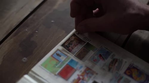 Closeup Highangle View of Unrecognizable Mature Adult Male Inserting Postage Stamps at Collection