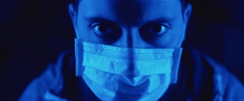 Man Puts on Medical Mask in Blue Light