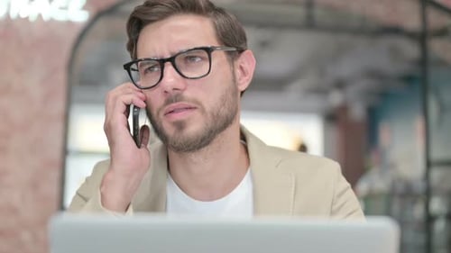 Close Up of Man with Laptop Talking on Smartphone