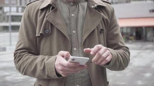 Joven irreconocible escribiendo en el teléfono inteligente y deslizando la pantalla hacia arriba. Caucásico concentrado