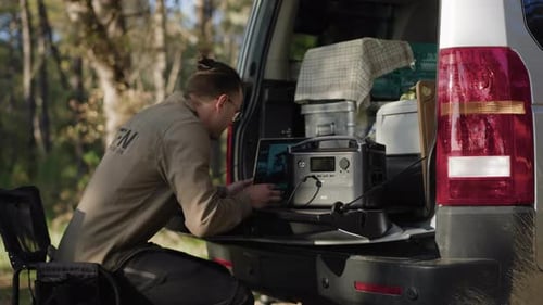 nômade digital sentado na tampa do porta-malas para trabalhar em seu computador
