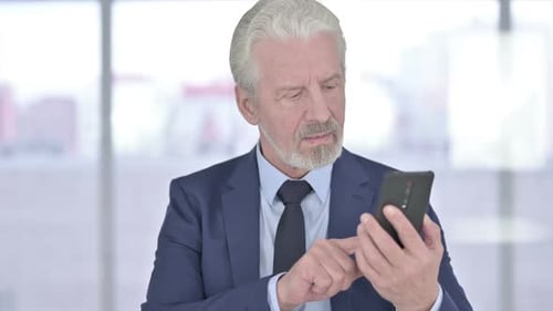 Gray Haired Man Uses Phone, Gives Thumbs Up