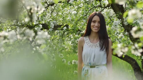 Young Woman Posing in a Blooming Apple Orchard