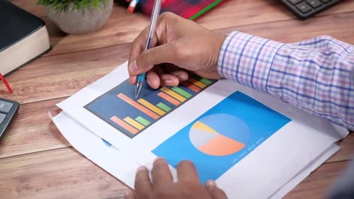 Menschenhand mit Stift Analysieren von Balkendiagramm auf Papier