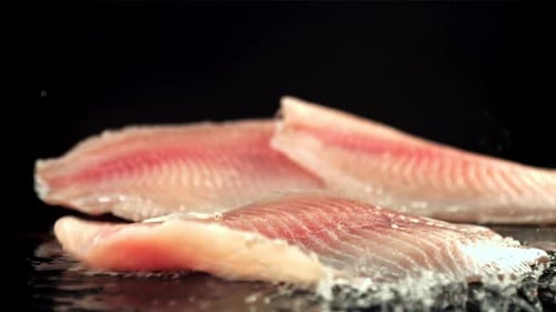 Fischfilets fallen mit Spritzern auf einen nassen Tisch