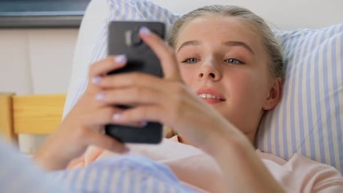 Teenager Lying in Bed Using Smartphone