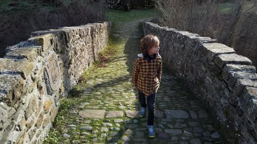 Garçon joyeux jouant sur le vieux pont dans la vallée de la forêt
