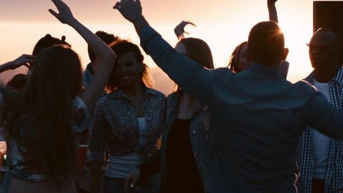 Young Adults Celebrate at Rooftop Party at Sunset