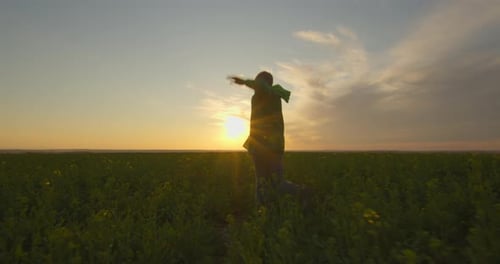 The Boy-superhero Is Running and Jumping on the Field. Sunset.