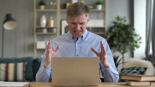 Man Working on Laptop Crying At Desk