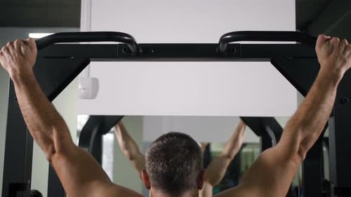 A Man with a Muscular Back Pulls Up on a Simulator Slow Mo