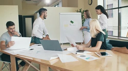 Professionals Discussing Charts at Meeting in Bright Office