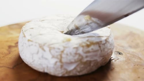 Cheese Wheel Being Cut with a Knife