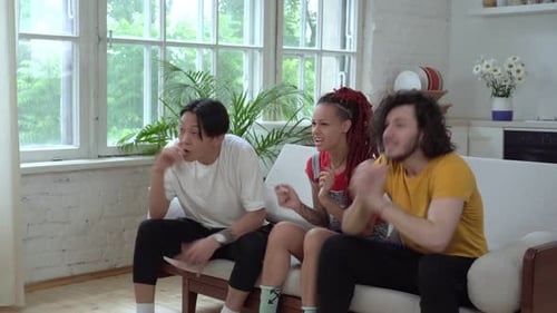 Friends Cheering Together on Sofa Indoors