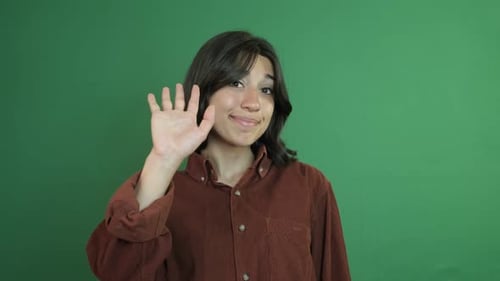 Smiling Young Adult Waving Hello on Green Screen