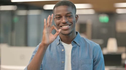 Young Adult Giving OK Hand Gesture in Office