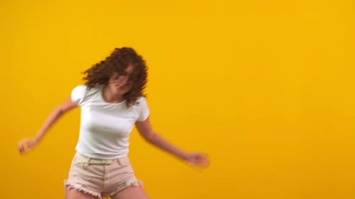 Young Woman Dancing with Energy on Yellow Background