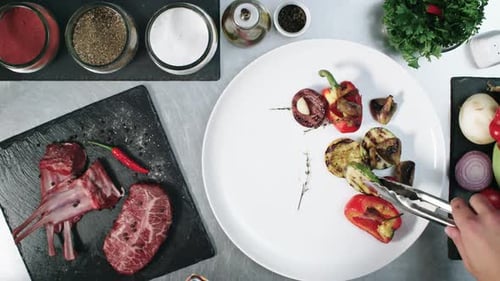 Chef Plating Steak with Grilled Vegetables Overhead