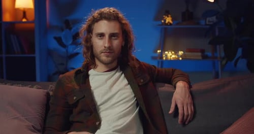 Portrait of Young Hipster Guy in Casual Clothes Relaxing on Sofa in Evening, Millennial Bearded Man