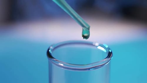 In a Laboratory a Scientist with a Pipette Analyzes a Colored Liquid