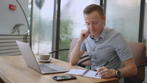 Schöner männlicher Entwickler oder Student, der im Café per Laptop studiert