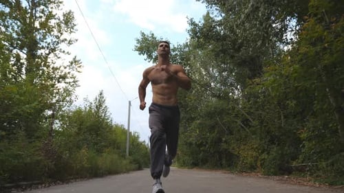 Handsome Sportsman Sprinting Fast Along Road with Beautiful Landscape at Background