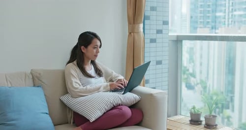 Woman Using Laptop Relaxing on Couch at Home