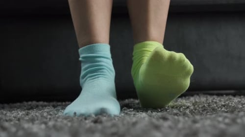 Individual Putting on Colorful Socks at Home