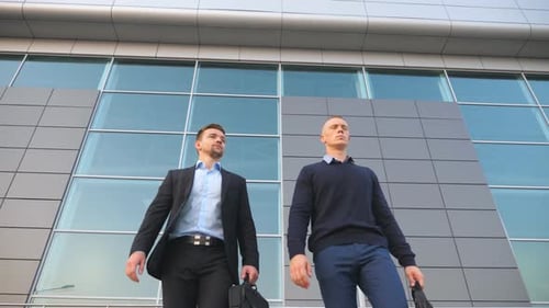 Low Angle View of Two Happy Young Businessmen with Briefcases Funny Dancing