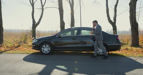 Businessman Talking on Phone by Parked Car