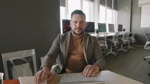 Middle-Aged Businessman Talking on Video Call in Office