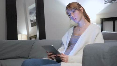 Woman Uses Tablet While Relaxing on Couch at Home